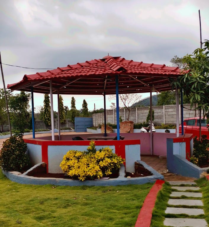 Landscaped garden gazebo with flowering plants at Kanchan Farmhouse
